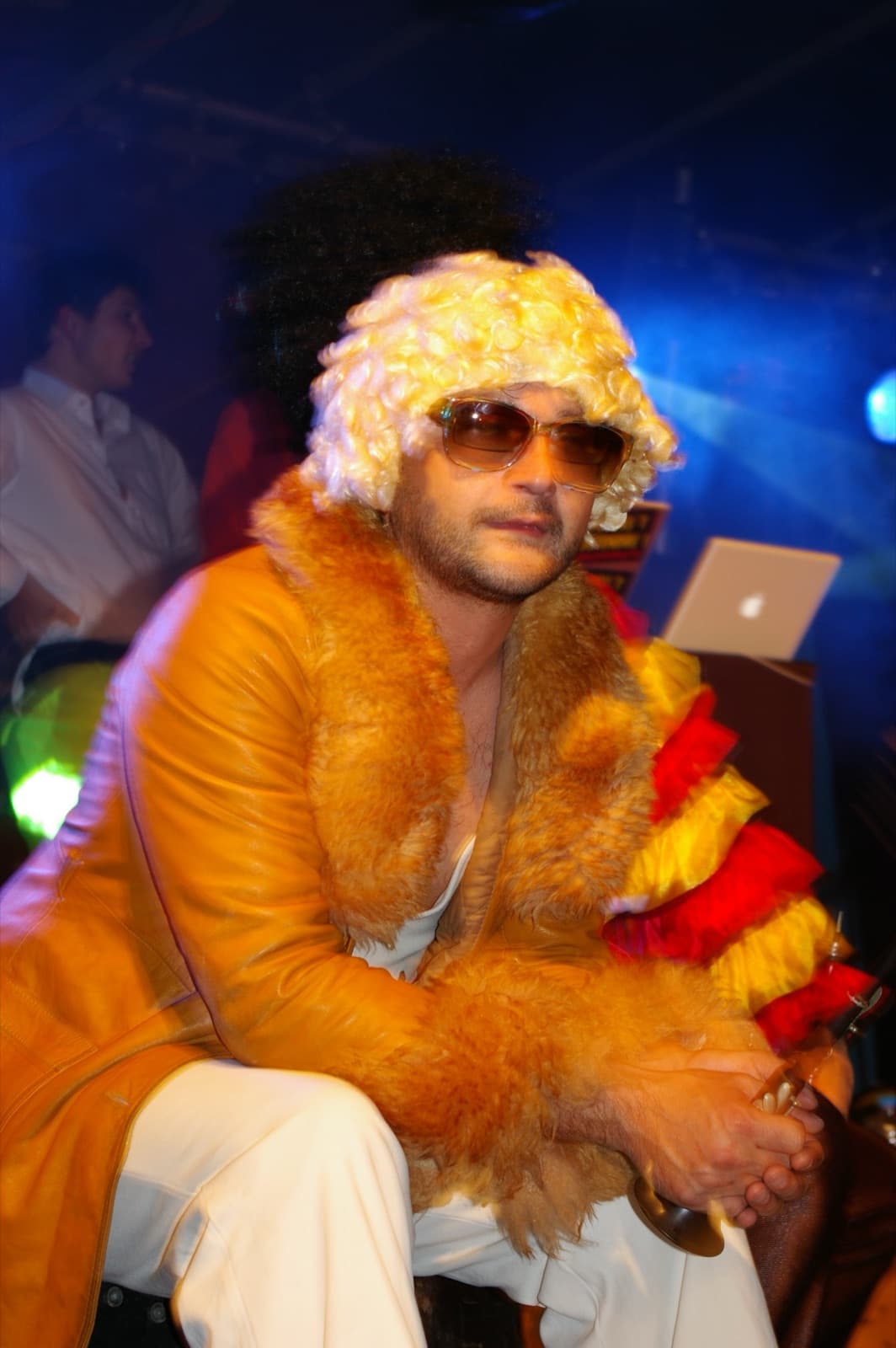 Un musicien des Groove Boys en manteau orange, perruque blonde et lunettes de soleil, sa bombarde à la main