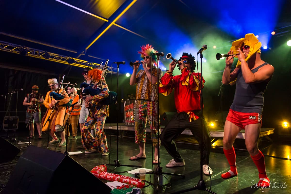 Les Groove Boys au Festival Kann al Loar, alignés sur scène avec leurs cornemuses et bombardes sous les lumières bleues et jaunes